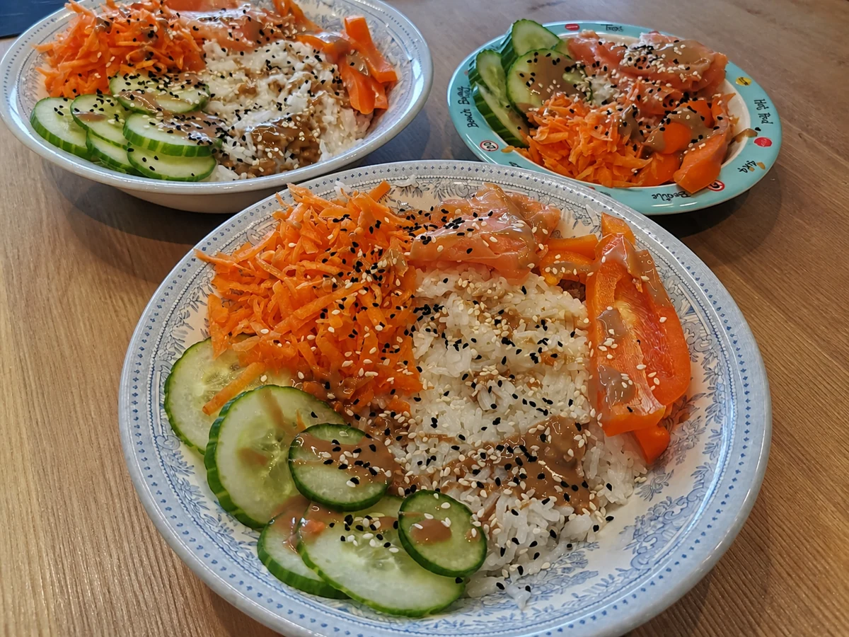 Finished salmon poke bowl with rice, cucumber, carrot and pepper